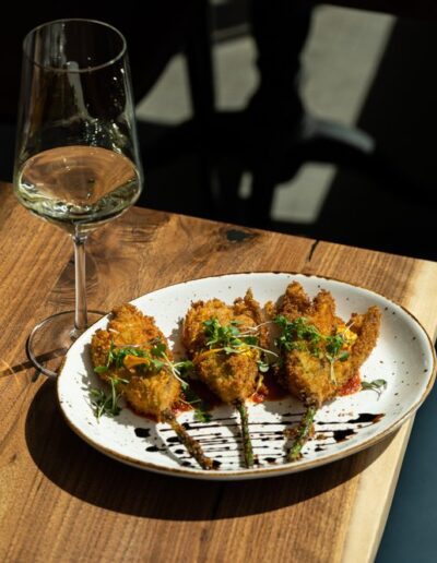 A plate of food on a table next to a glass of wine.